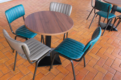 Round dining table with black cast iron base with dining chairs in various colours.