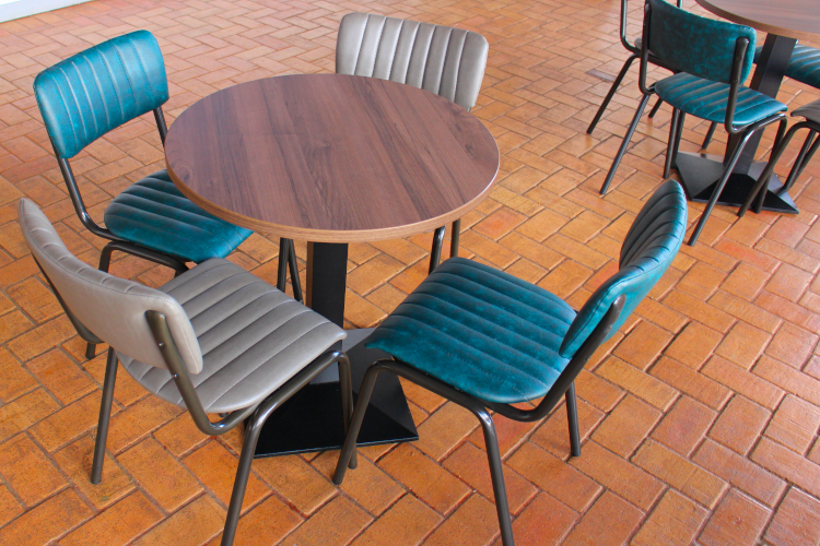Round dining table with black cast iron base with dining chairs in various colours.