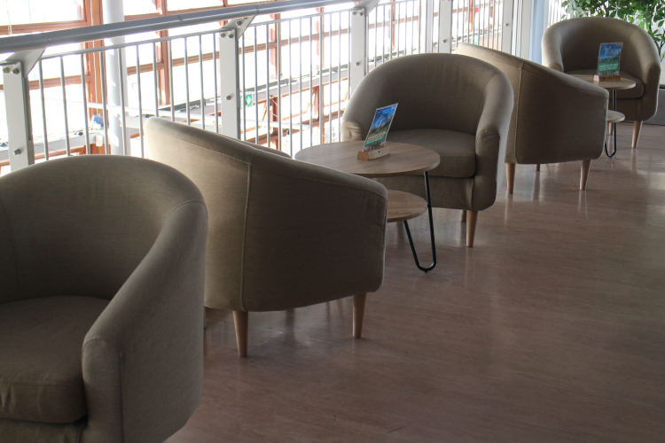 Natural coloured tub chairs on a balcony, with small coffee tables.