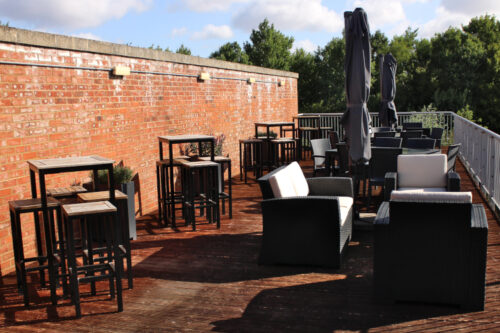 rattan and wooden furniture on an open air terrace in a forest.