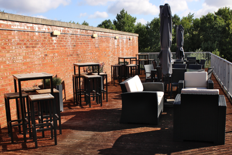 rattan and wooden furniture on an open air terrace in a forest.