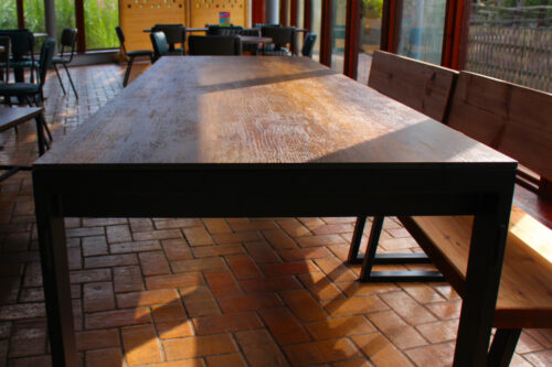 Large dining table detail with brick flooring and wooden benches.