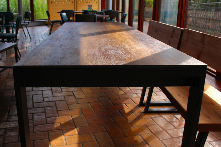 Large dining table detail with brick flooring and wooden benches.