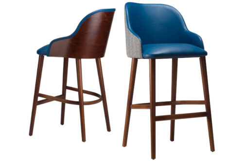 Front view of a bar stools, side by side with arms. Both with blue faux leather and Walnut stained legs. One with an upholstered back, the other wooden back, both on a white background.